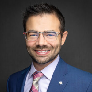 Dr. Nicholas A. Flugstad in a blue business suit and glasses